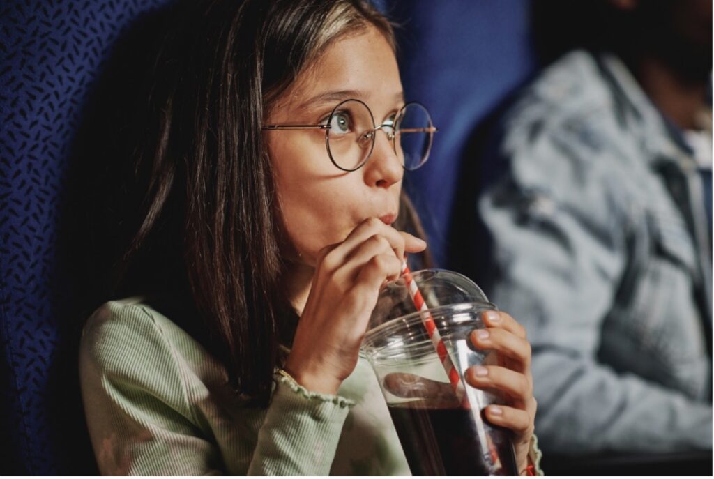 A person drinking sugary drink from a glass with straw