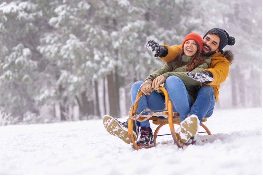 A person and person sledding in the snow, Dashing Through the Snow: 12 Holistic Dental Tips for a Merry Holiday