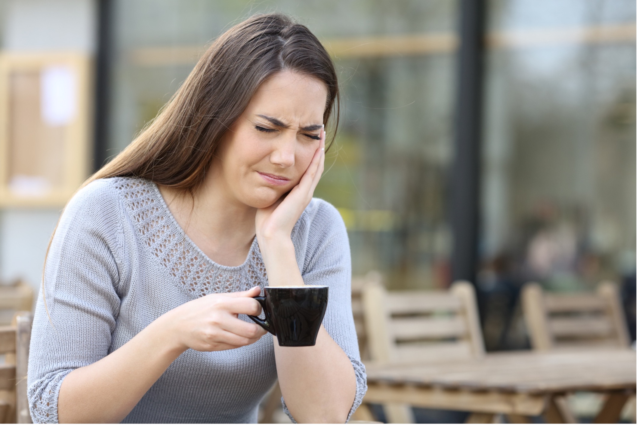 A person holding a cup of coffee and their mouth, Understanding Tooth Sensitivity